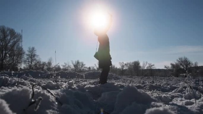 女人试图在冬天通过太阳举起智能手机来捕捉移动信号