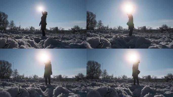 女人试图在冬天通过太阳举起智能手机来捕捉移动信号