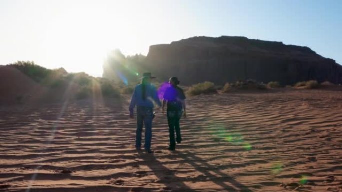 丈夫和妻子在与家人度过美好的一天后，手牵着手，散步和聊天，他们与家人在一起，亚利桑那州纪念碑谷纳瓦霍