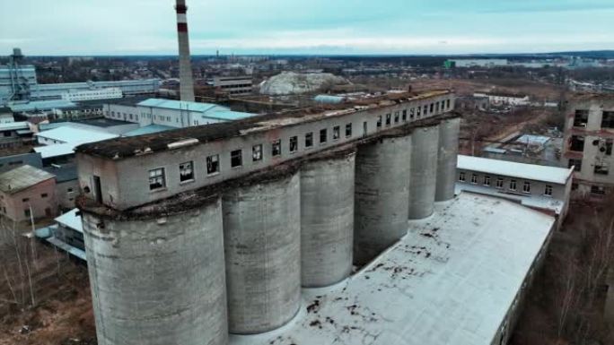 旧化工厂建设。毁坏的长仓库建在高混凝土水库的顶部。背景下的现代工业厂房和城市。
