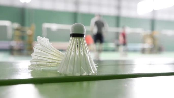 羽毛球场的羽毛球比赛在打羽毛球运动员的背景下。