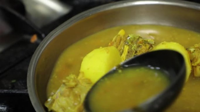 男人的手做饭，在煎锅里炖土豆和鱼。倒入酱汁。印度语、阿拉伯语、菜肴。