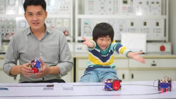 亚洲学生和老师在实验室中测试在路线上运行的机器人机器人汽车，并带有传感器响应。建筑师设计电路和会议共