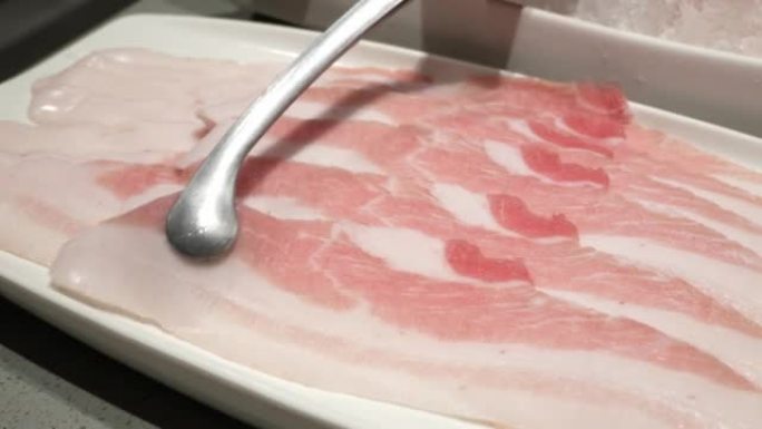 使用筷子采摘新鲜的生猪肉切片