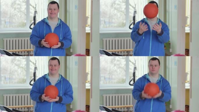 一个患有唐氏综合症的开朗残疾人的肖像，对着镜头微笑并与篮球合影。前视图。