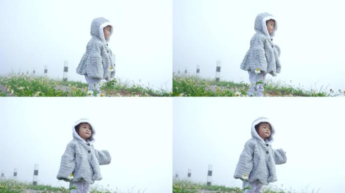 4K，可爱的小女孩穿长袖，长腿帽子，雾蒙蒙的早晨很冷，女孩正走在鲜花浓雾笼罩的周围，小Sa的眼睛高兴