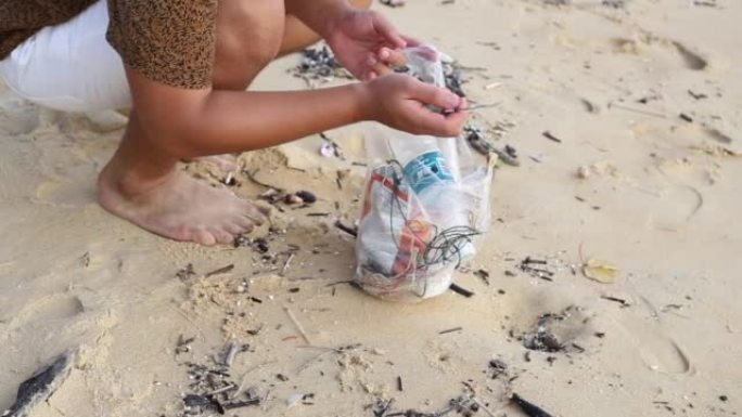 亚洲当地人拿着装满从海滩上带走的垃圾的塑料。水平。