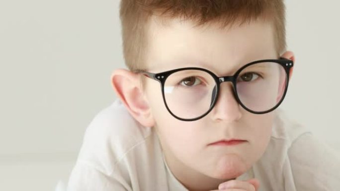 戴眼镜的男孩正认真地看着镜头。特写。好奇的学龄前男孩肖像。4k