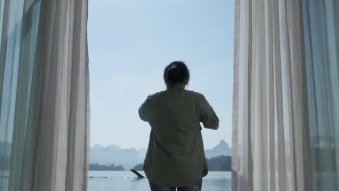 亚洲妇女敞开大门，在度假胜地欣赏山景和湖景