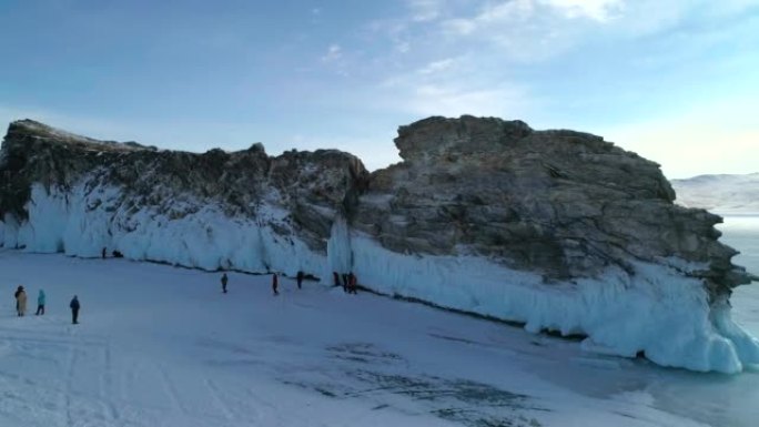 贝加尔湖岩石冰覆盖的岛屿上的鸟瞰图。成群的游客在裂开的冰上走来走去。著名的旅游景点。贝加尔湖美丽的冬