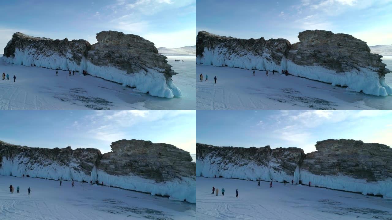 贝加尔湖岩石冰覆盖的岛屿上的鸟瞰图。成群的游客在裂开的冰上走来走去。著名的旅游景点。贝加尔湖美丽的冬