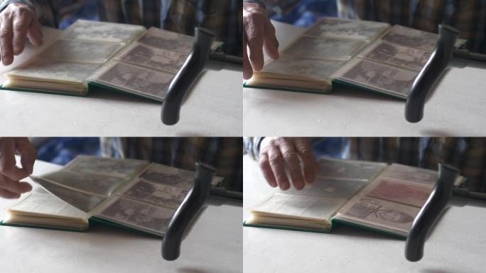 一位老人的手翻过家庭相册的页面。彭蒙纳 (penmoner) 用拐杖坐着，检查房子的旧照片。选择性聚