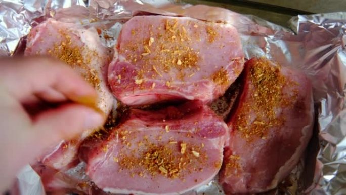 箔纸上的生肉牛排。猪肉撒上香料。不用油烹饪。准备在烤箱里做饭。