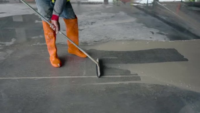 4K，用塑料汁液排斥水的建筑工人的脚底中等射击。清洁在施工现场工作时充满脏水的水泥地板。