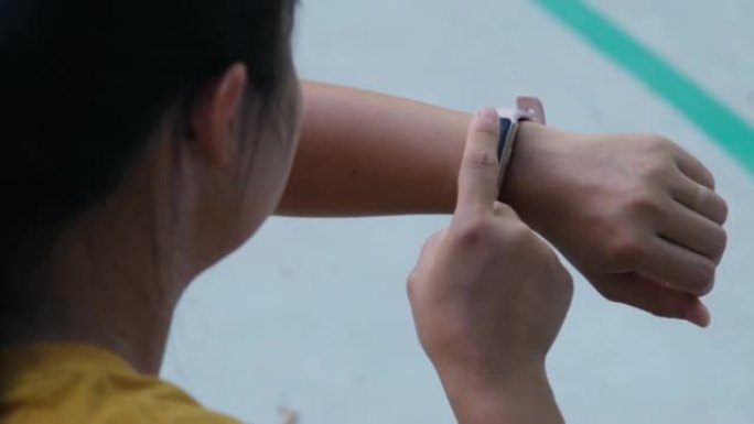 一个女跑步者计算智能手表上燃烧的卡路里的特写镜头。一名年轻运动员在户外练习时使用智能手表检查结果。