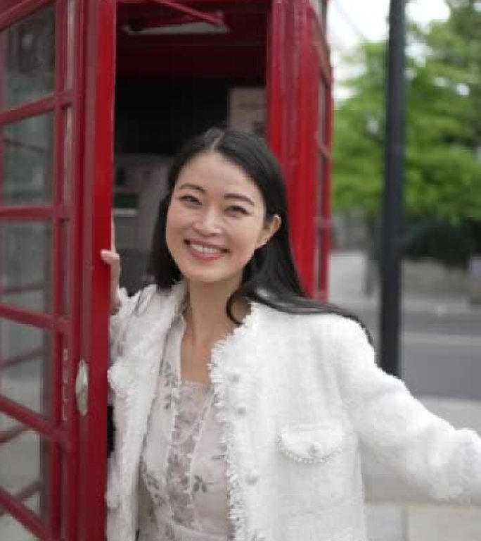 一个年轻的女人在摆弄一个标志性的红色电话亭