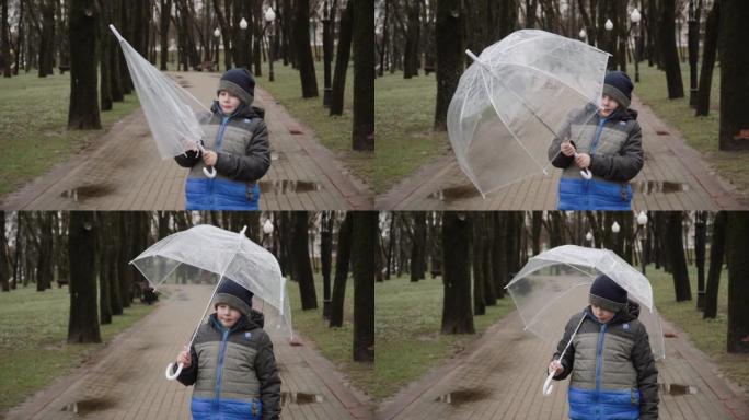 穿夹克的男孩站在公园潮湿的人行道上。孩子按下按钮打开伞。