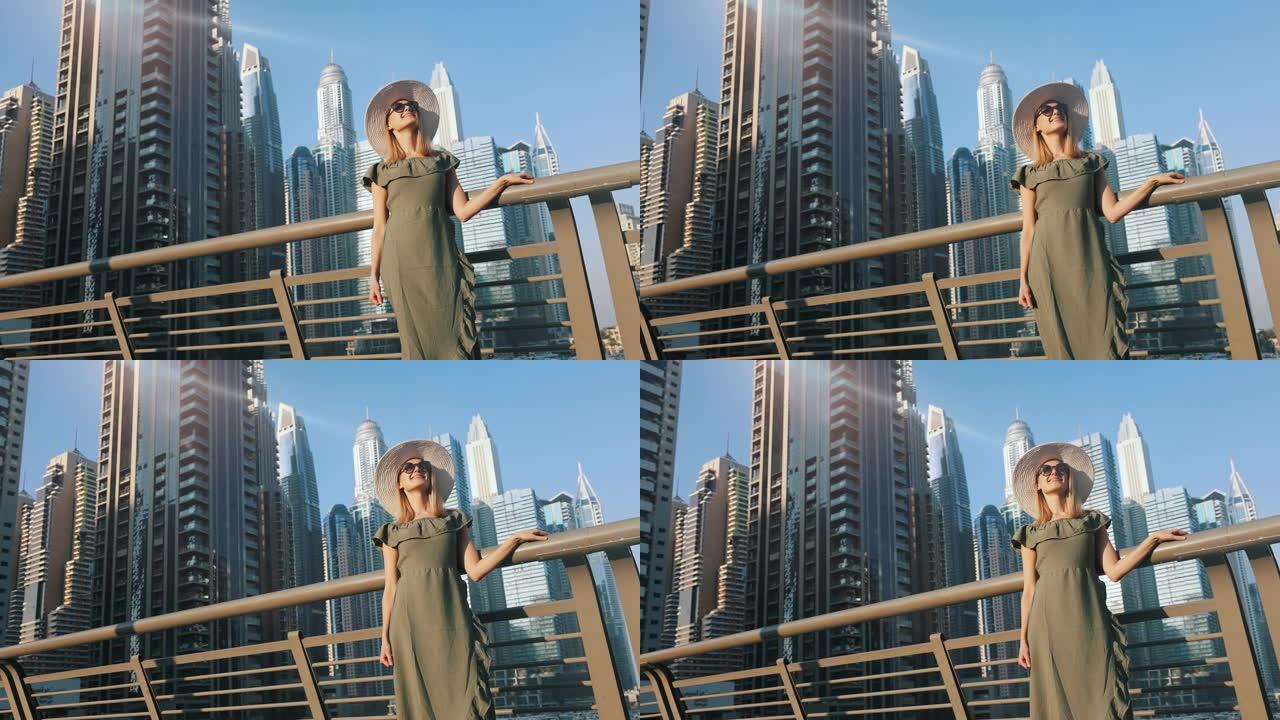 穿着绿色连衣裙和帽子的时尚女性享受迪拜城市建筑。阿拉伯联合酋长国旅游