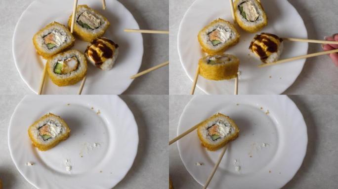 用筷子拍摄的带有寿司的盘子的特写镜头。日本餐厅点了一套寿司。选择性聚焦。开胃烤寿司在餐馆用筷子吃