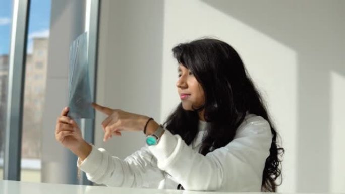 在诊所实习的年轻印度医学生。白大褂女医生拿着听诊器检查x光片