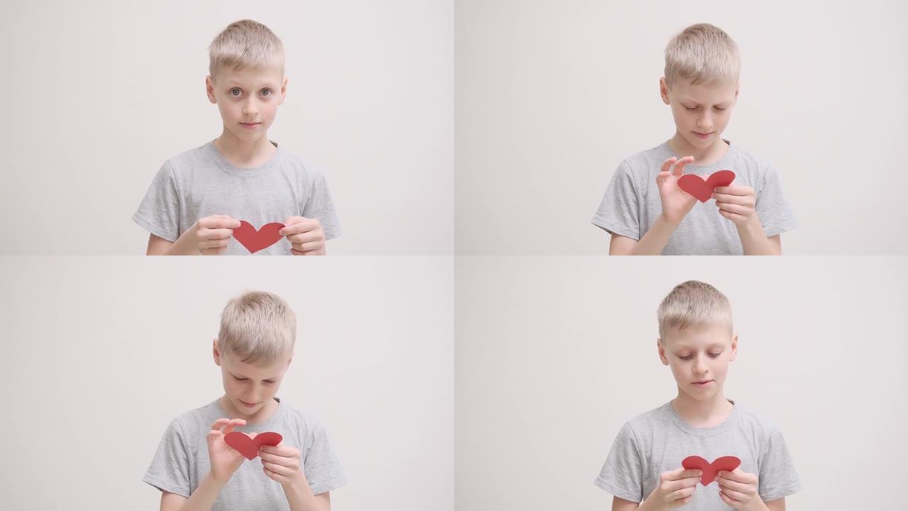 可爱的男孩拿着一张红心形状的情人卡，阅读并微笑着。情人节，2月14日。爱，情感，感觉