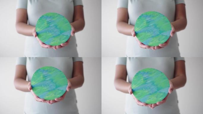 女人手握纸地球符号