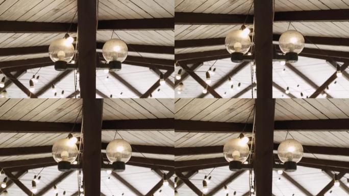 屋顶下木杆上有节能发光二极管灯泡的圆形玻璃旧灯。