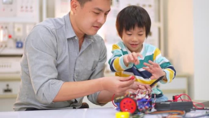 亚洲学生和老师使用电子仪表和笔记本电脑在科学课中构建自主自驱动机器人汽车的原型