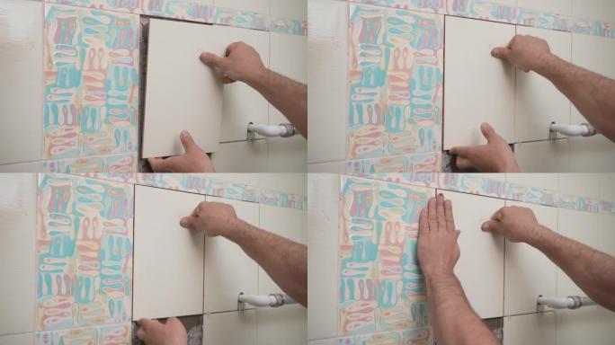男工师傅在浴室的墙壁上铺设瓷砖。修理工在装修工作中双手放置瓷砖。