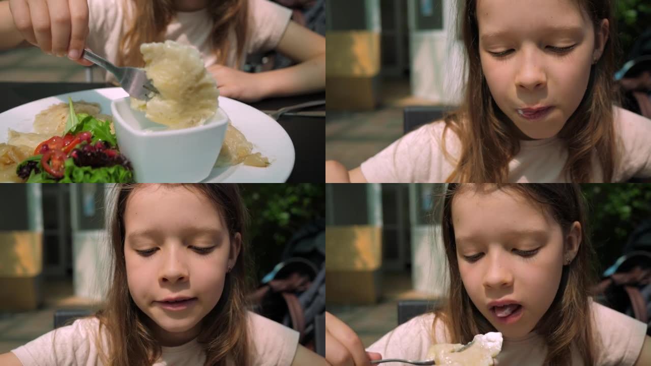 小女孩贪婪地吃美味的土豆饺子，用叉子蘸上土豆饺子，在餐馆的肖像视图中