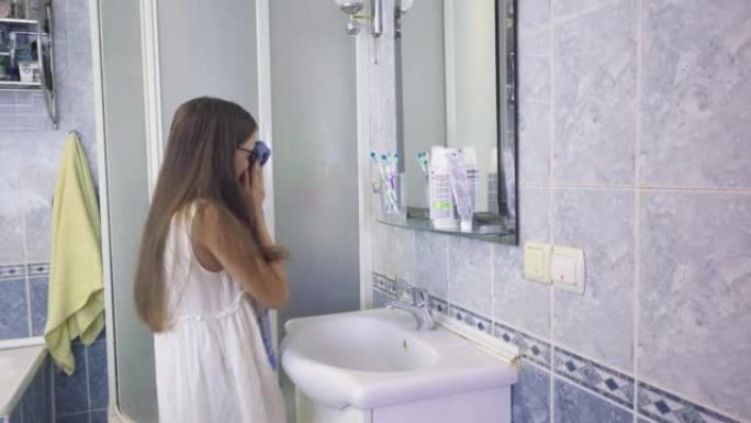 一个戴眼镜的少女用水洗脸，然后用毛巾和树叶擦拭嘴唇。