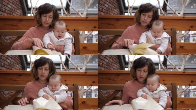 母亲在餐厅里带着婴儿翻阅菜单孩子放进嘴里纸角用舌头好奇的认知