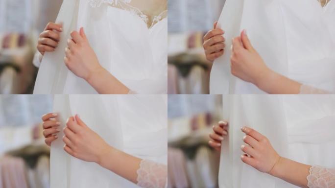 女人的手轻轻触摸白色连衣裙。特写手拍
