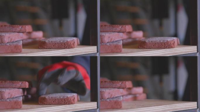 橡胶工作手套的工匠小心地从仓库架子上的易碎瓷砖模仿砖，将其包装和出售或交付给客户，关闭。