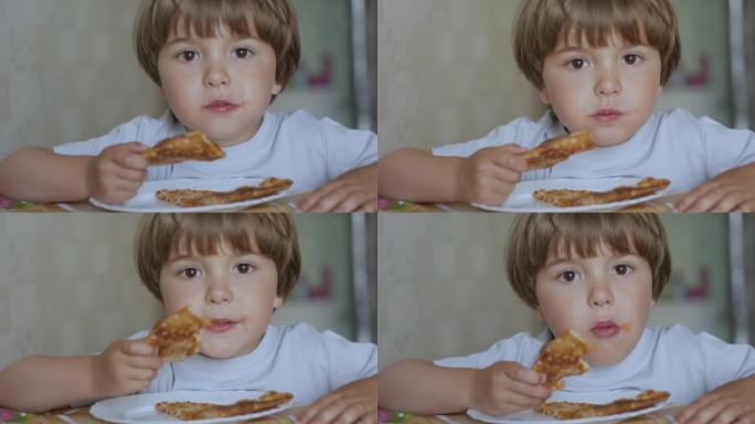 孩子吃披萨。饥饿的小男孩坐在厨房的餐桌上，从盘子里吃美味的意大利披萨。不健康的营养快餐。一个孩子吃午