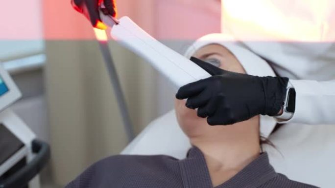 美容师正在使用宽带光设备来恢复女性面部皮肤的活力