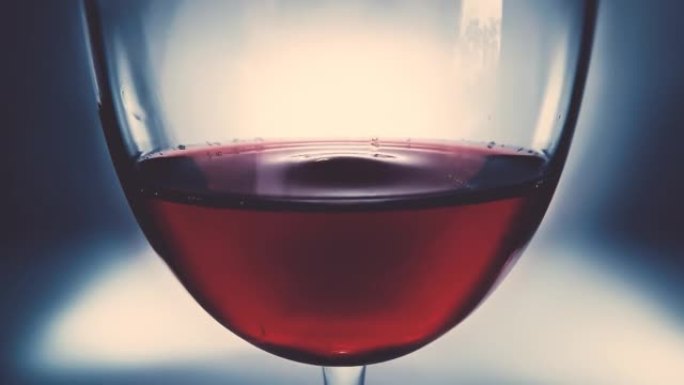 创意微距慢动作4k视频红酒在一杯和一滴落的酒。酒滴在玻璃杯中慢慢落下特写。在高速电影摄像机上拍摄。