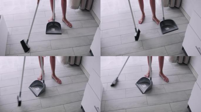 一名年轻女子在家用扫帚扫地。