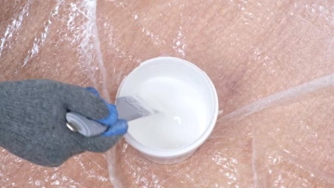 一个人用特殊的塑料搅拌器搅拌白色丙烯酸涂料。粉刷门。