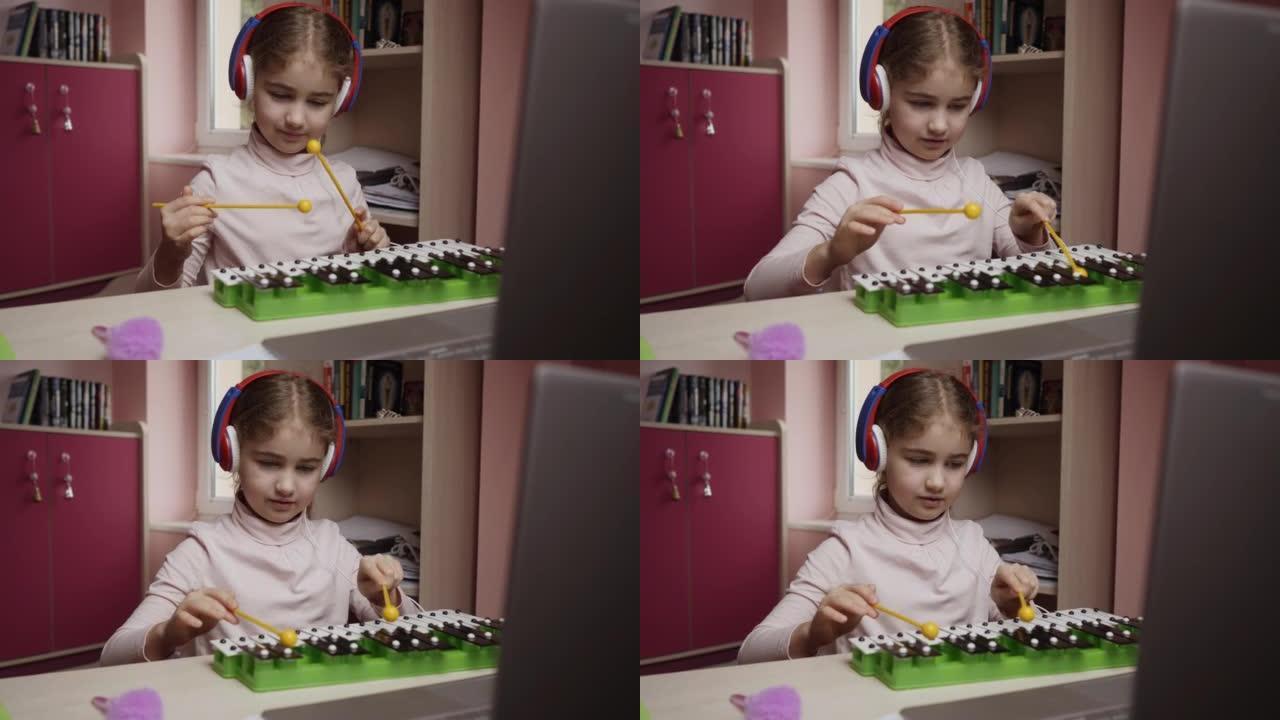 高加索女孩学习弹木琴、钢琴。远程学习。女学生使用笔记本电脑音乐课在线学习。学生戴着耳机观看互联网视频
