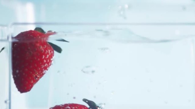 草莓落入水中，新鲜浆果，鸡尾酒和饮料