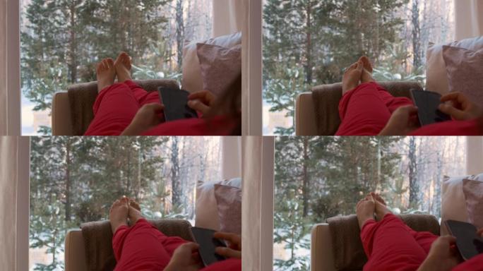 一个穿着红色衣服的女孩躺在沙发上，俯瞰着被雪覆盖的后院。一个年轻的女人没有注意到她周围的美丽，埋在她