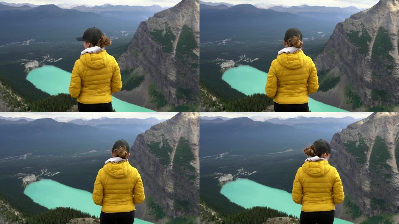 女徒步旅行者在加拿大艾伯塔省班夫国家公园的魔鬼拇指了望台欣赏路易丝湖的景色