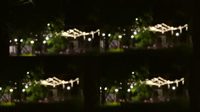 晚上在公园灯光场的晚宴在花园悬挂模糊拍摄