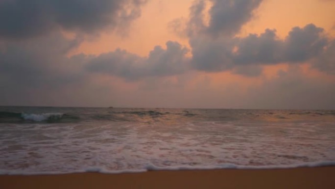 在印度果阿的北果阿，美丽华海滩的广角慢动作拍摄日落时分，海洋上空有云彩。日落后，海面上的云波与戏剧性