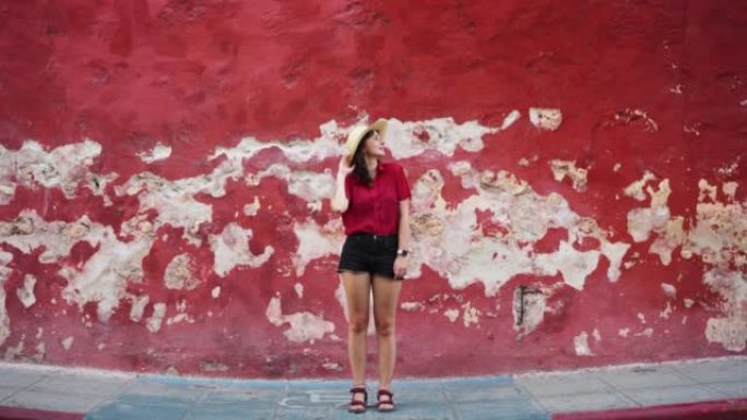 站在旧红墙背景上的女人