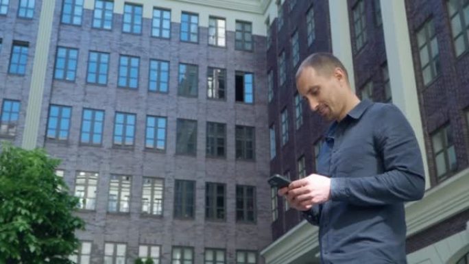 年轻人在现代建筑的背景下走在城市中，并使用智能手机