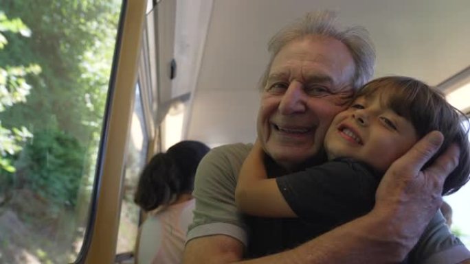 祖父和孙子在乘火车旅行时拥抱。祖父母在靠窗的铁路运输中拥抱孙子。世代爱情概念