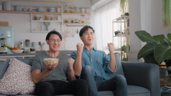 两名年轻的亚洲男子在体育频道看电视