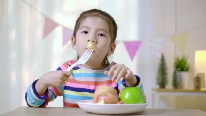 儿童亚洲女孩在桌子上吃苹果，健康饮食习惯概念